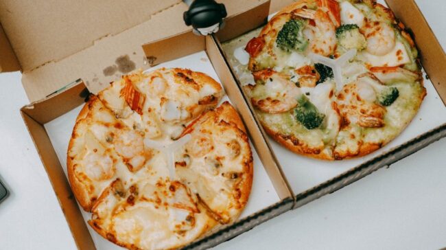 Two tasty shrimp pizzas with vegetables in delivery boxes on a table. - Photo by FOX ^.ᆽ.^= ∫ on Pexels