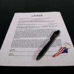 Lease agreement document with pen and American flag keychain on a black table. - Photo by Artful Homes on Pexels